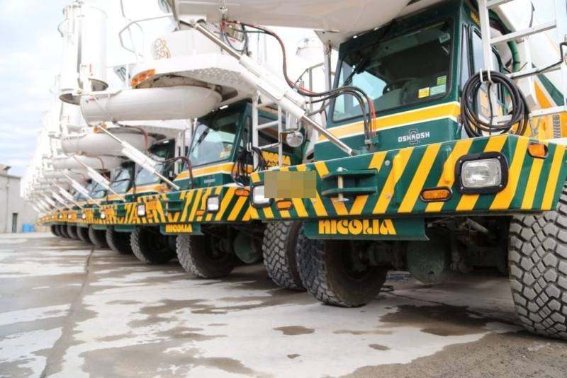 Row of Nicolia Oshkosh front-discharge mixers, gold chevron bumpers